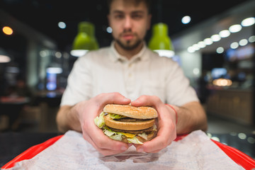 Great tasty burger in the hands of a man. Focus on the burger. Fast Food Concept.