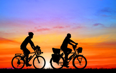 Fototapeta premium Silhouette man and bike relaxing on blurry sunrise background