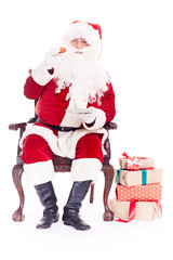 Portrait of Santa Claus sitting in chair and eating cookies isolated on white