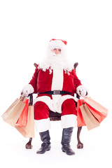 Santa sitting in chair and holding bunches of bags after Christmas shopping