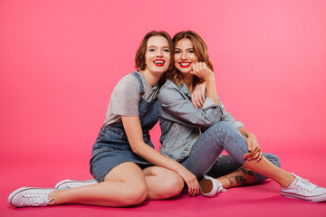 Obraz na płótnie Canvas Cheerful two women friends sitting on floor