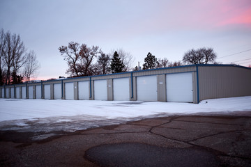 Row of garages in winter snow at sunset