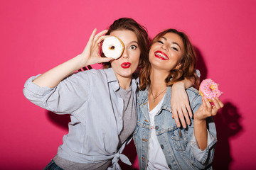 Amazing two women friends eating donuts