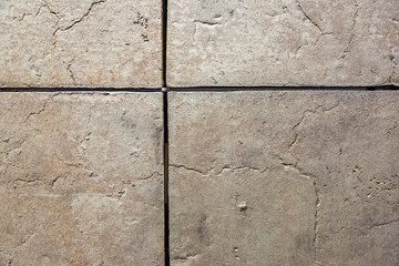 Textured tiled floor. Square beige tiles with patterns
