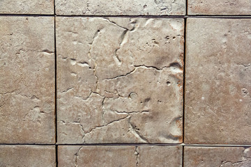 Textured tiled floor. Square beige tiles with patterns
