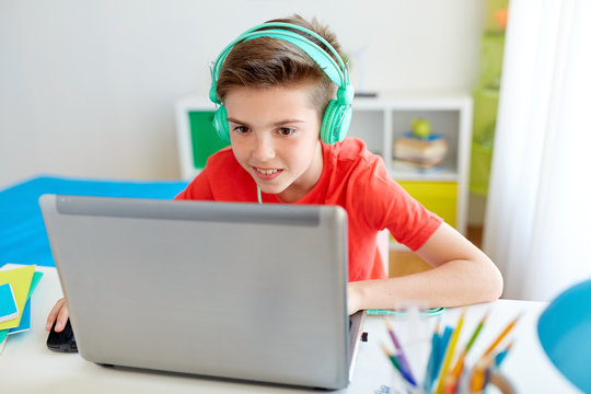 boy in headphones playing video game on laptop
