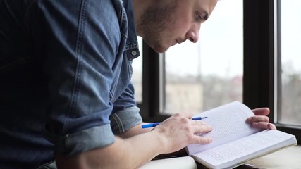 Pan of young man studying near the window