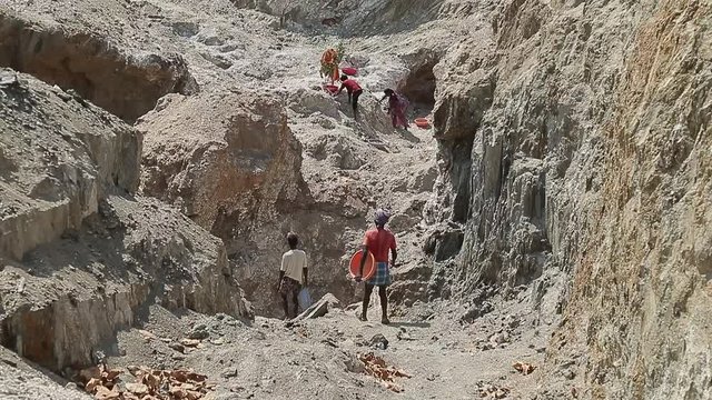 Employment and manual labor in India, poor unrecognisable men Indian mine worker comes with empty basins. Mining minerals in third world countries.
