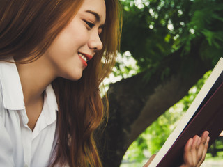 Close up face of young woman reading book at the park.