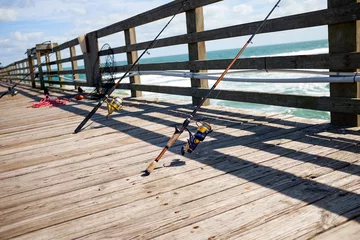 Fototapeten Fishing rods on a wooden marine jetty or pier © Colby