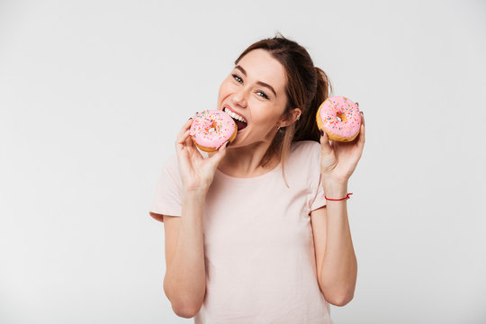 Portrait of a cheerful pretty girl eating donuts