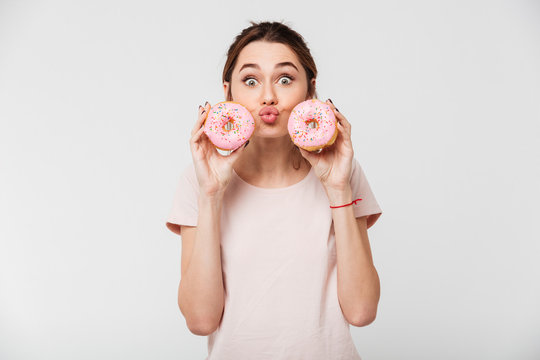 Portrait of a cheery girl holding donuts at her face