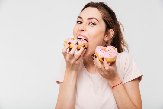 Close up portrait of a hungry greedy girl eating donuts