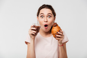 Portrait of a cheery pretty girl eating croissant