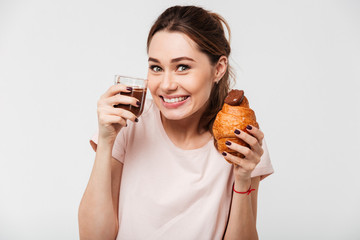 Portrait of a satisfied pretty girl eating croissant