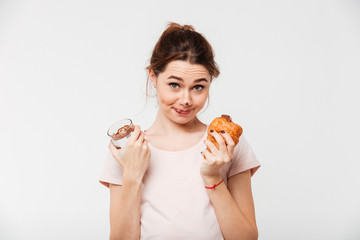 Portrait of a smiling pretty girl eating croissant