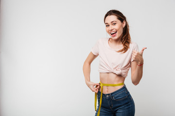 Portrait of a slim satisfied woman holding measuring tape