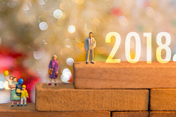Miniature group happy family holding balloons standing on wooden 2018 with party happy new year, party background.