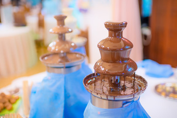 Fototapeta na wymiar Chocolate fondue fountain. Sweets and dessert decoration.