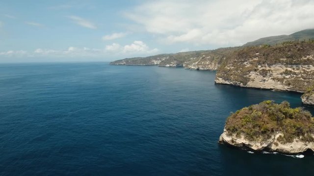 Seascape, rocky coast, ocean, blue sea, waves, Nusa Penida, Indonesia. Aerial view Ocean with waves and rocky cliff. 4K video. Travel concept. Aerial footage