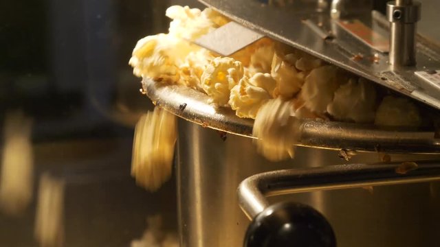 Close up shot of popcorn popping out of the pop corn machine