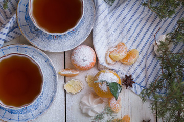 Tea in beautiful porcelain cups. New Year's morning. Mandarins and cups of tea on a white wooden background. Top view.