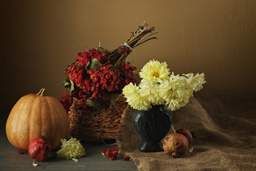Fototapeta premium Rowan with daisies, near a basket with pomegranate