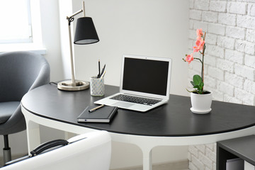 Comfortable workplace with laptop on table in office