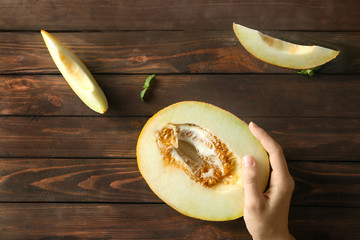 Young woman with yummy melon at wooden table