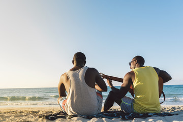 Two cuban friends having fun in the beach with his guitar.