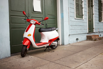 Red and white scooter parked outside a green door