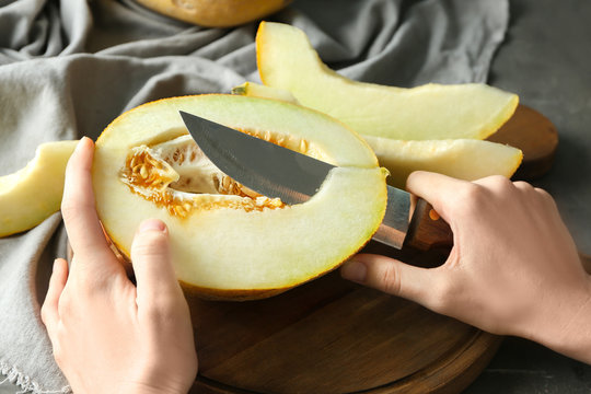 Young woman cutting yummy melon on wooden board