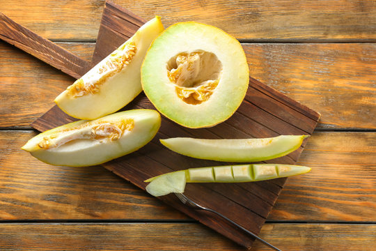 Board with yummy melon on wooden table