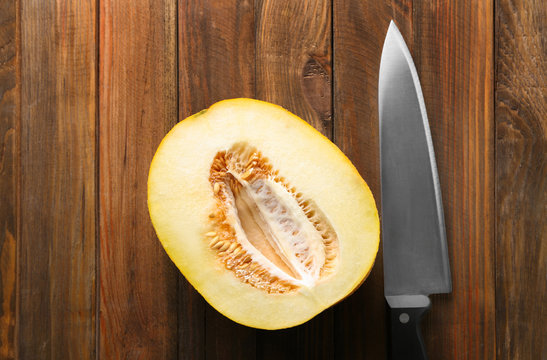 Yummy half of melon and knife on wooden table