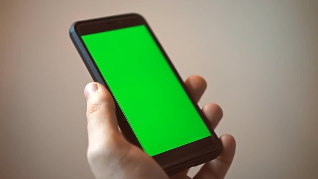 Hand holding mobile phone with green screen. Chroma key.