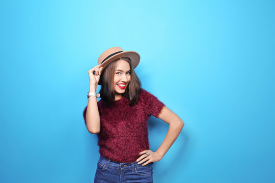 Attractive hipster girl in hat on color background