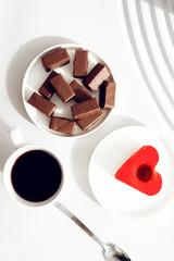 Food photography coffee and a heart-shaped cake. Nearby lie chocolate sweets. Sweets view from above