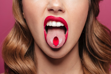 Cropped image of young lady with red lips holding pill in mouth