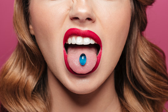 Cropped image of young lady with blue lips holding pill in mouth