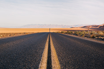 Empty road passing through desert against sky
