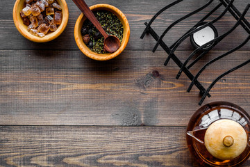 Tea break. Tea pot, sugar and tea leaves on dark wooden background top view copyspace