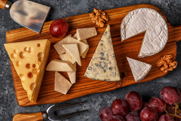 Assorted cheeses on wooden board.