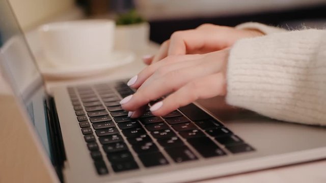Closeup of business woman typing on laptop. Female hands busy typing on keyboard. Freelancer girl working at home in winter. Slow motion. Camera rotating, dolly