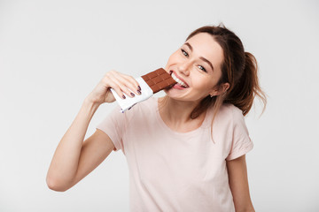 Portrait of a smiling pretty girl biting chocolate bar