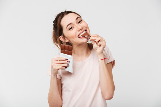 Portrait of a satisfied pretty girl biting chocolate bar