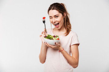 Portrait of a happy playful girl eating fresh salad