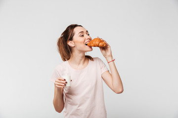 Portrait of a happy pretty girl eating croissant