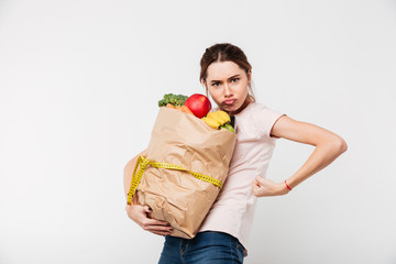 Portrait of a serious girl holding bag with groceries