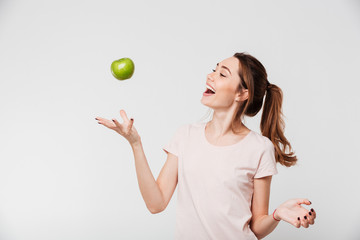 Portrait of a smiling girl throwing apple in the air