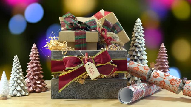 Large English style traditional Christmas hamper with paper wrapped gifts and food. static against bokeh lights of Christmas Tree.